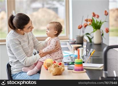 remote job, multi-tasking and family concept - mother with baby working at home office. mother with baby working at home office