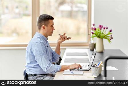 remote job, technology and business concept - middle-aged man with laptop computer calling on smartphone or using voice command recorder at home office. man with smartphone and laptop at home office