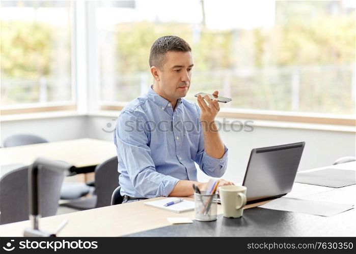 remote job, technology and business concept - middle-aged man with laptop computer calling on smartphone or using voice command recorder at home office. man with smartphone and laptop at home office