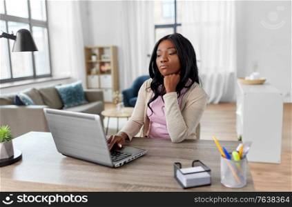 remote job, technology and people concept - african american bored or tired young woman with laptop computer working at home office. bored woman with laptop working at home office