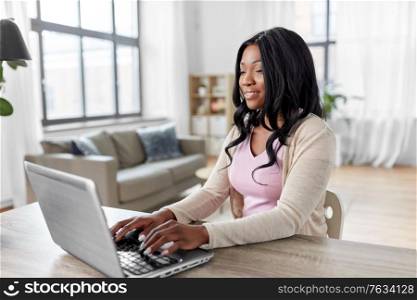 remote job, technology and people concept - african american young woman with laptop computer working at home office. woman with laptop working at home office
