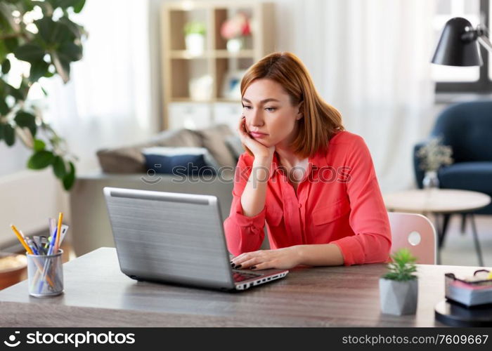 remote job, technology and people concept - bored or tired young woman with laptop computer working at home office. bored woman with laptop working at home office