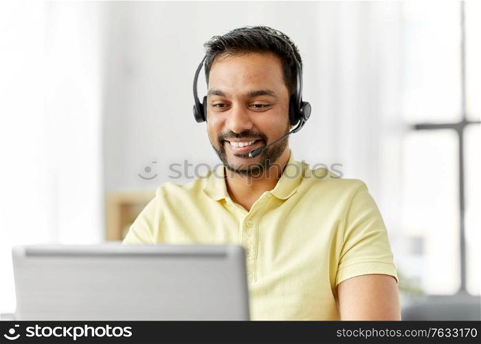 remote job, technology and people concept - happy smiling indian man with headset and laptop computer having conference call at home office. indian man with headset and laptop working at home