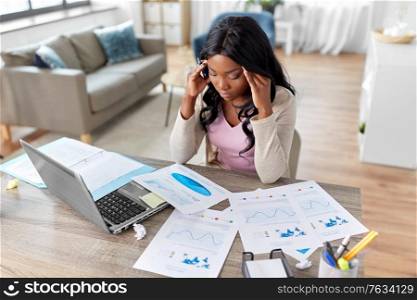 remote job, technology and people concept - stressed young african american woman with laptop computer and papers working at home office. stressed woman with papers working at home office