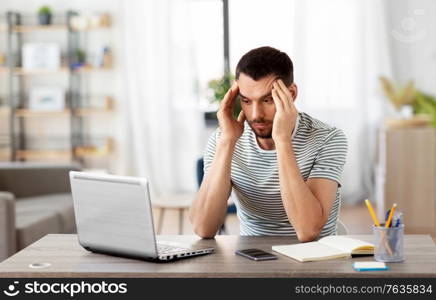 remote job, technology and people concept - stressed young man with laptop computer working at home office. stressed man with laptop working at home office