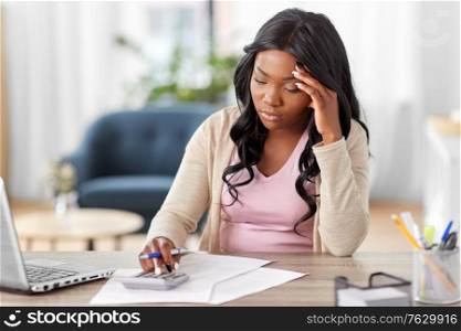 remote job, technology and people concept - young african american woman with calculator and papers working at home office. woman with calculator and papers working at home