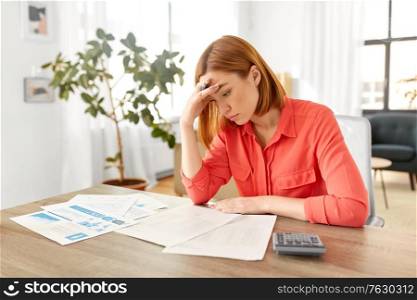 remote job, technology and people concept - young woman with calculator and papers working at home office. woman with calculator and papers working at home