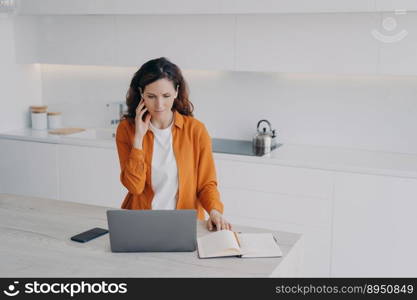 Remote teacher having class via zoom at home. Teacher has conference using earphone and laptop. Happy european woman has conference at kitchen. E-learning and online school on quarantine.. Remote teacher having class via zoom at home. Teacher has conference using earphone and laptop.