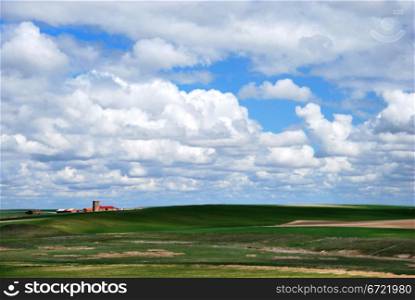 Remote village in the green meadow under cloudy blue sky