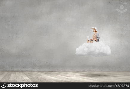 Remote work. Woman in dress and hat sitting on cloud and working on laptop