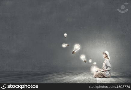 Remote work. Woman in dress and hat sitting on floor and working on laptop