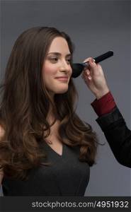 removing excess of powder using fan brush - professional makeup artist working