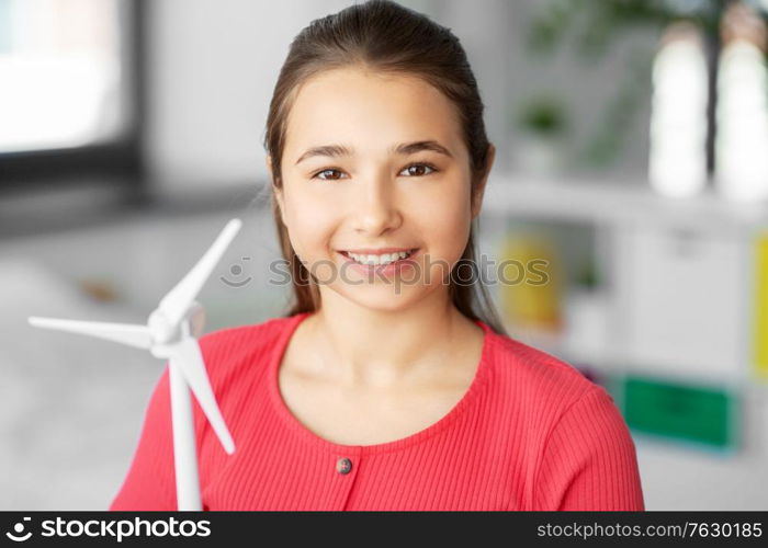 renewable energy, ecology and people concept - portrait of happy smiling teenage girl with with toy wind turbine at home. happy teenage girl with toy wind turbine