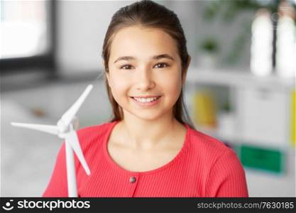 renewable energy, ecology and people concept - portrait of happy smiling teenage girl with with toy wind turbine at home. happy teenage girl with toy wind turbine