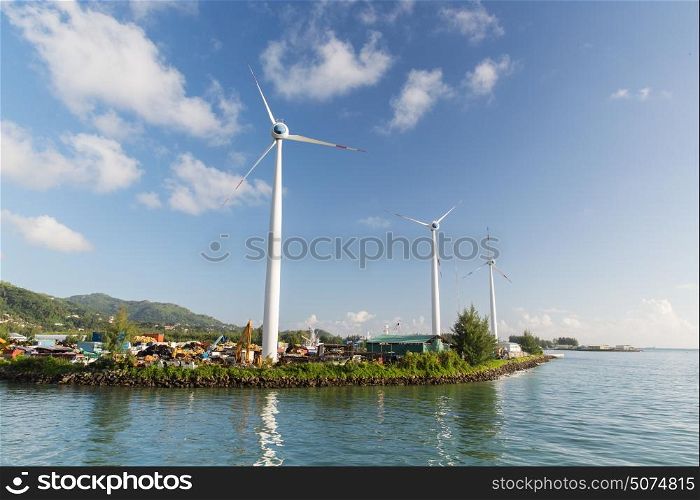 renewable energy, technology and power concept - turbines at wind farm on sea shore. turbines at wind farm on sea shore