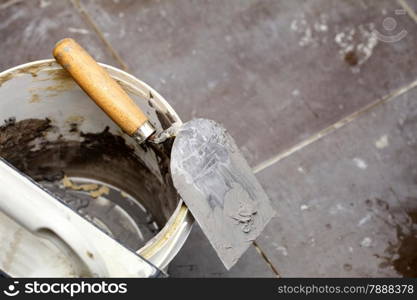 Renovation at home dirty trowel and bucket with mortar on construction building site