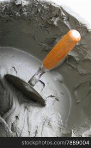 Renovation at home dirty trowel and bucket with mortar on construction building site