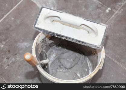 Renovation at home dirty trowel and bucket with mortar on construction building site