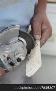 Renovation at home worker cuts tile with angle grinder electric tool man is tiling at home construction site