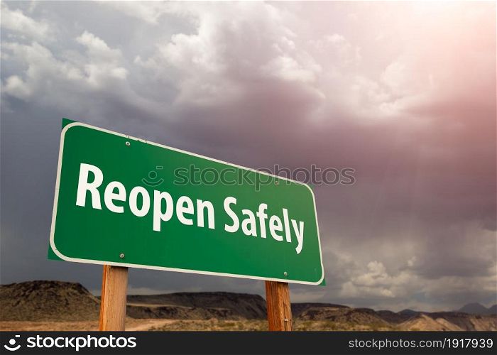 Reopen Safely Green Road Sign Against Ominous Stormy Cloudy Sky.