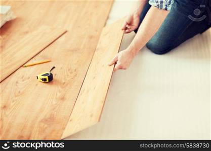 repair, building and home concept - close up of male hands intalling wood flooring