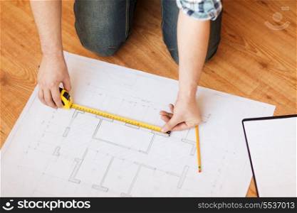 repair, building and home concept - close up of male hands measuring blueprint