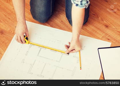 repair, building and home concept - close up of male hands measuring blueprint