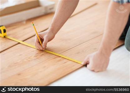 repair, building and home concept - close up of male hands measuring wood flooring