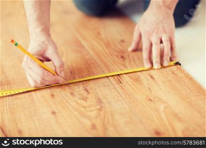 repair, building and home concept - close up of male hands measuring wood flooring