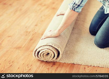 repair, building and home concept - close up of male hands unrolling carpet