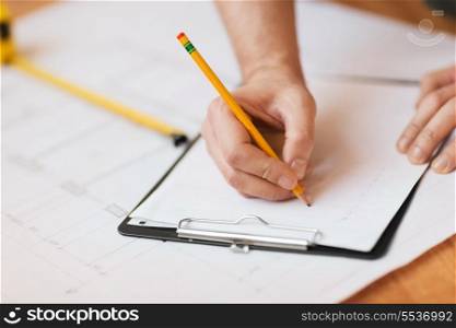 repair, building and home concept - close up of male hands writing in clipboard