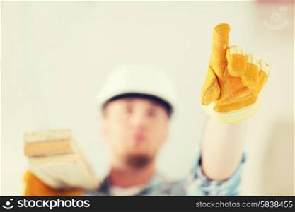 repair, building and home concept - close up of male in gloves and helmet carrying wooden boards on shoulder and pointing finger