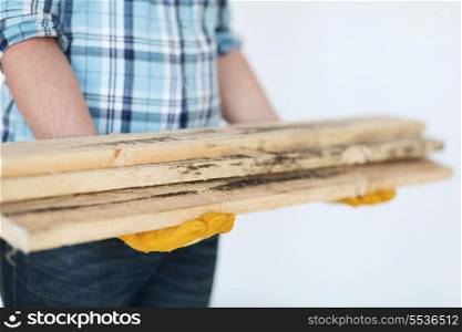 repair, building and home concept - close up of male in gloves carrying wooden boards