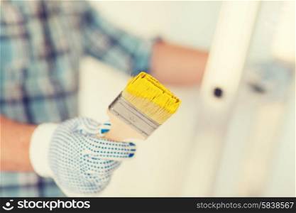 repair, building and home concept - close up of male in gloves holding paintbrush