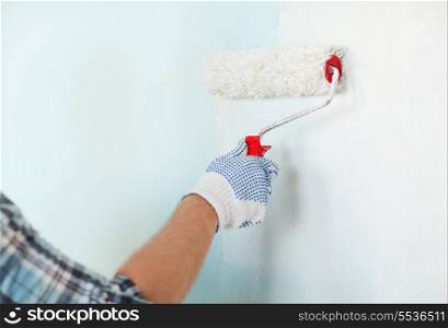 repair, building and home concept - close up of male in gloves painting wall with roller