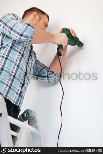 repair, building and home concept - close up of male with electric drill making hole in wall