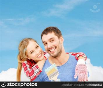 repair, building and home concept - smiling couple covered with paint with paint brush