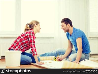 repair, building and home concept - smiling couple measuring wallpaper