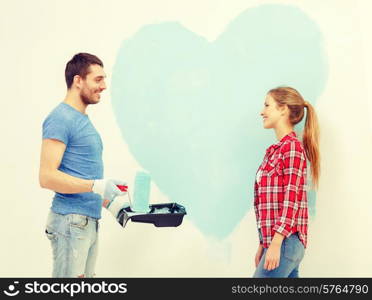 repair, building and home concept - smiling couple painting big heart on wall at home