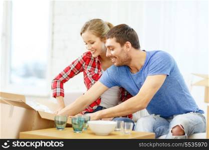 repair, building and home concept - smiling couple unpacking kitchenwear