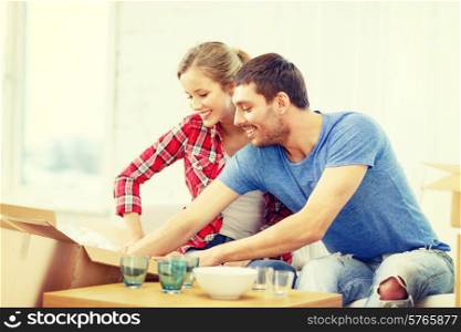 repair, building and home concept - smiling couple unpacking kitchenwear