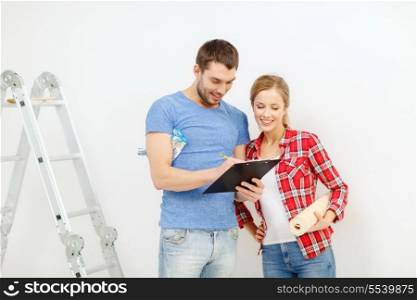 repair, building and home concept - smiling couple with clipboard, wallpaper roll and ladder