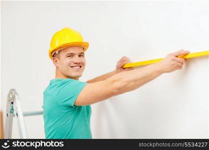 repair, building and home concept - smiling man in helmet building new home using spirit level to measure
