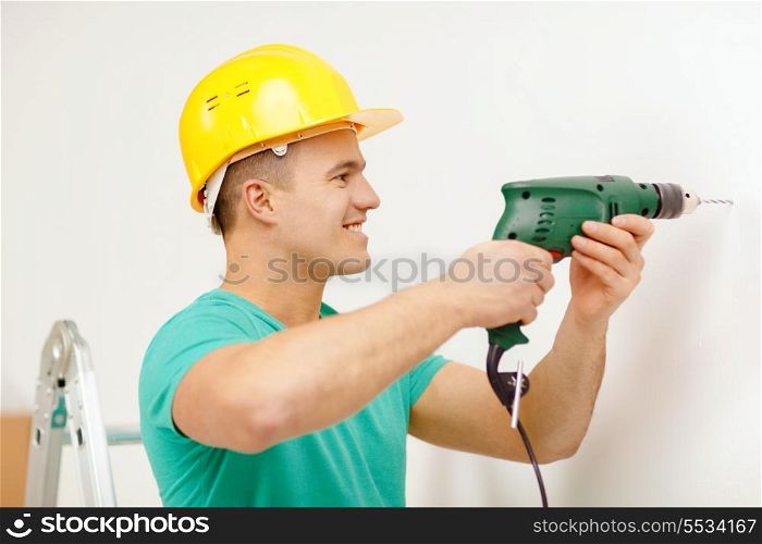 repair, building and home concept - smiling man in yellow protective helmet with electric drill making hole in wall