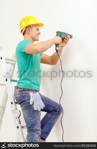 repair, building and home concept - smiling man in yellow protective helmet with electric drill making hole in wall