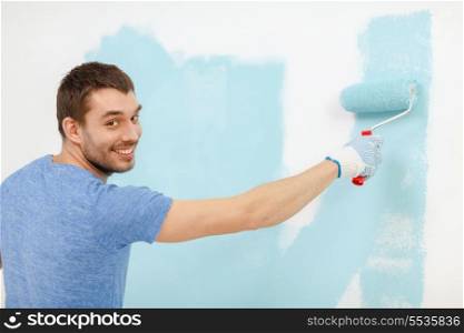 repair, building and home concept - smiling man painting wall at home