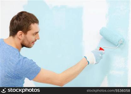 repair, building and home concept - smiling man painting wall at home