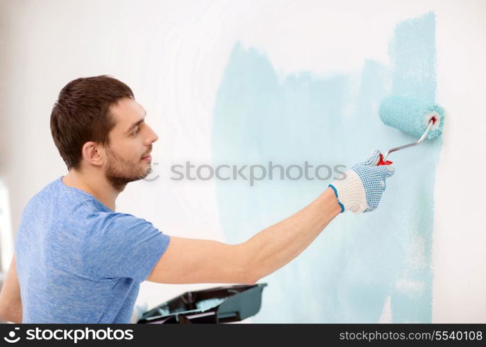 repair, building and home concept - smiling man painting wall at home