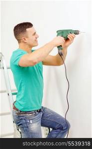 repair, building and home concept - smiling man with electric drill making hole in wall