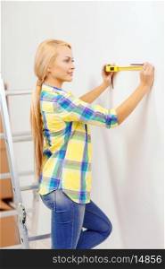repair, building and home concept - smiling woman measuring wall